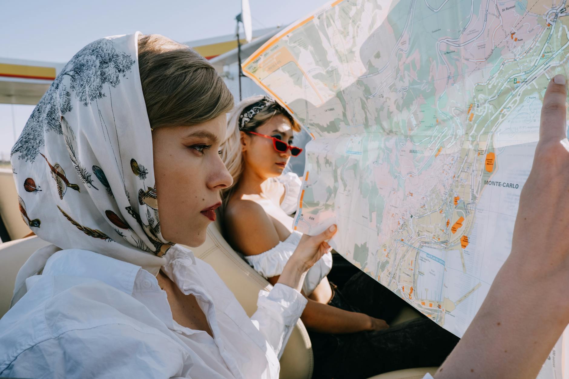 Women on a road trip holding a map in a convertible