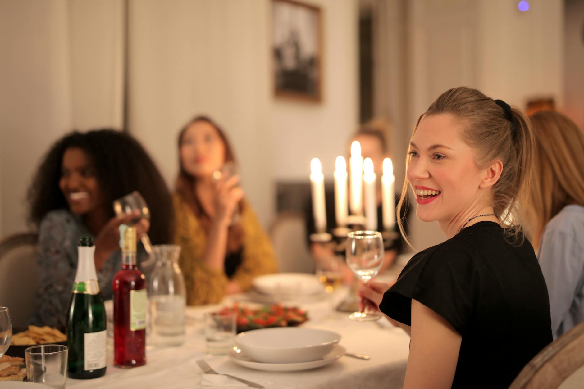 Diverse group of women at a candlelit dinner table