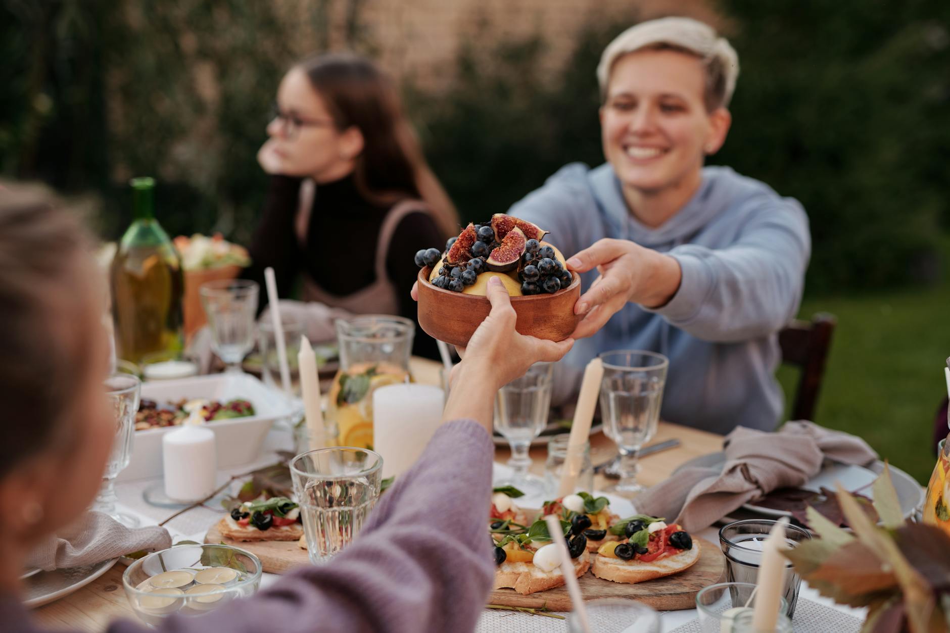 Friends sharing a Tuscan outdoor dinner with fresh figs and bread